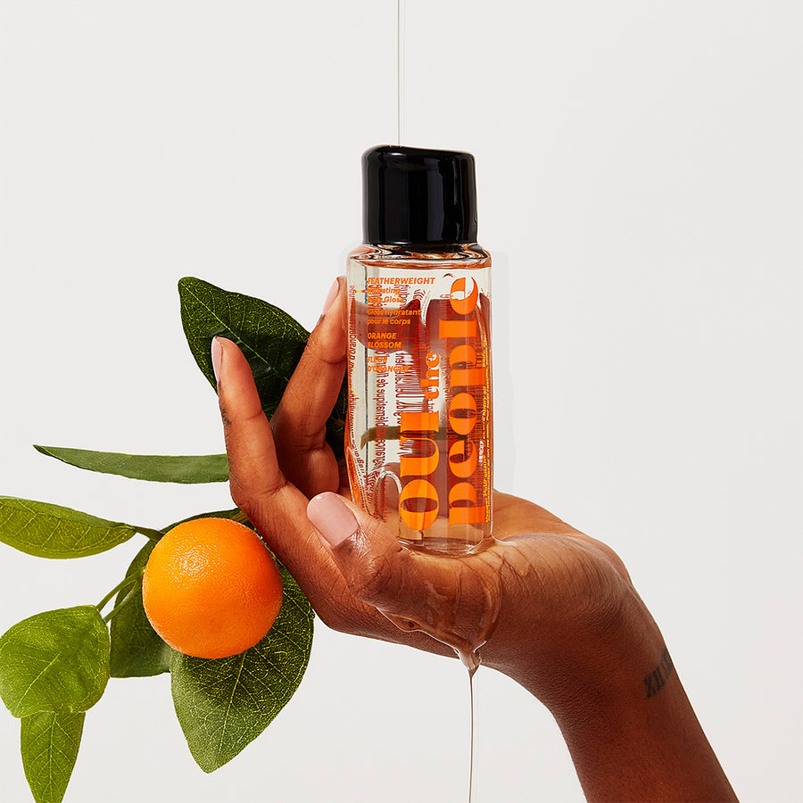 Hand holding FEATHERWEIGHT Hydrating Body Gloss Orange Blossom | Oui the People